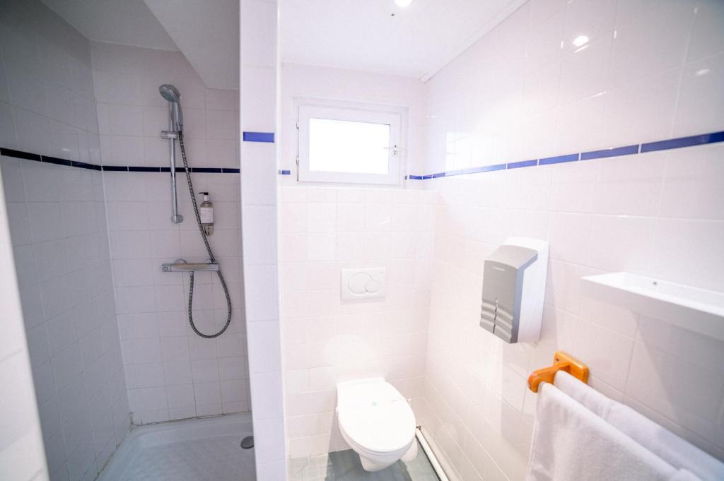 a white bathroom with a shower and a toilet at Hotel Atlantique in Mimizan-Plage