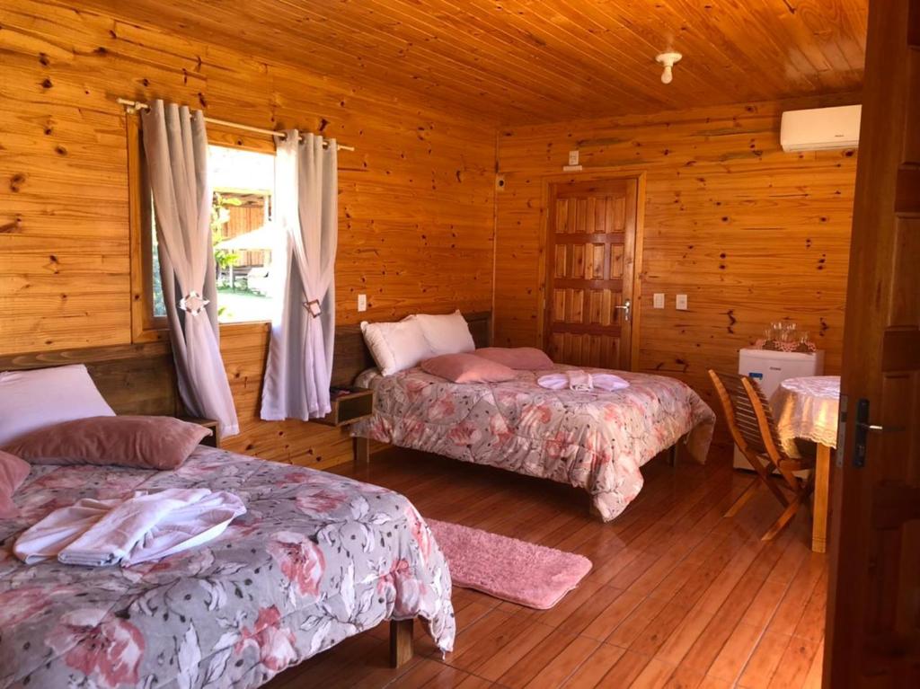 a bedroom with two beds in a wooden cabin at Pousada Santa Terezinha in Urubici