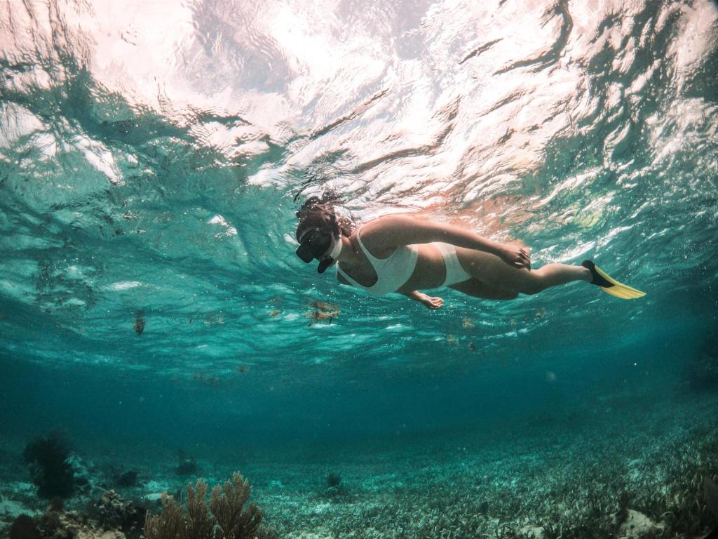 a woman swimming in the water with a frisbee at Portofino Beach Resort-An Authentic Island Escape! in San Pedro