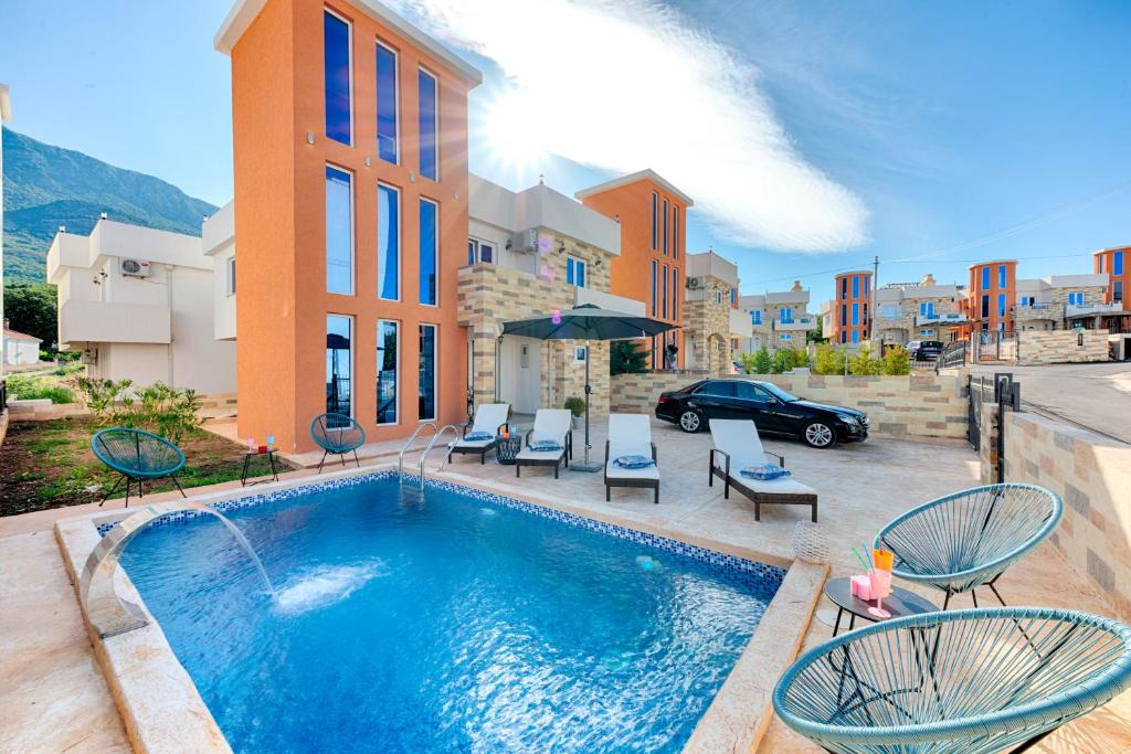 a swimming pool in front of a building with chairs and a car at Villa Panorama Hill in Dobra Voda