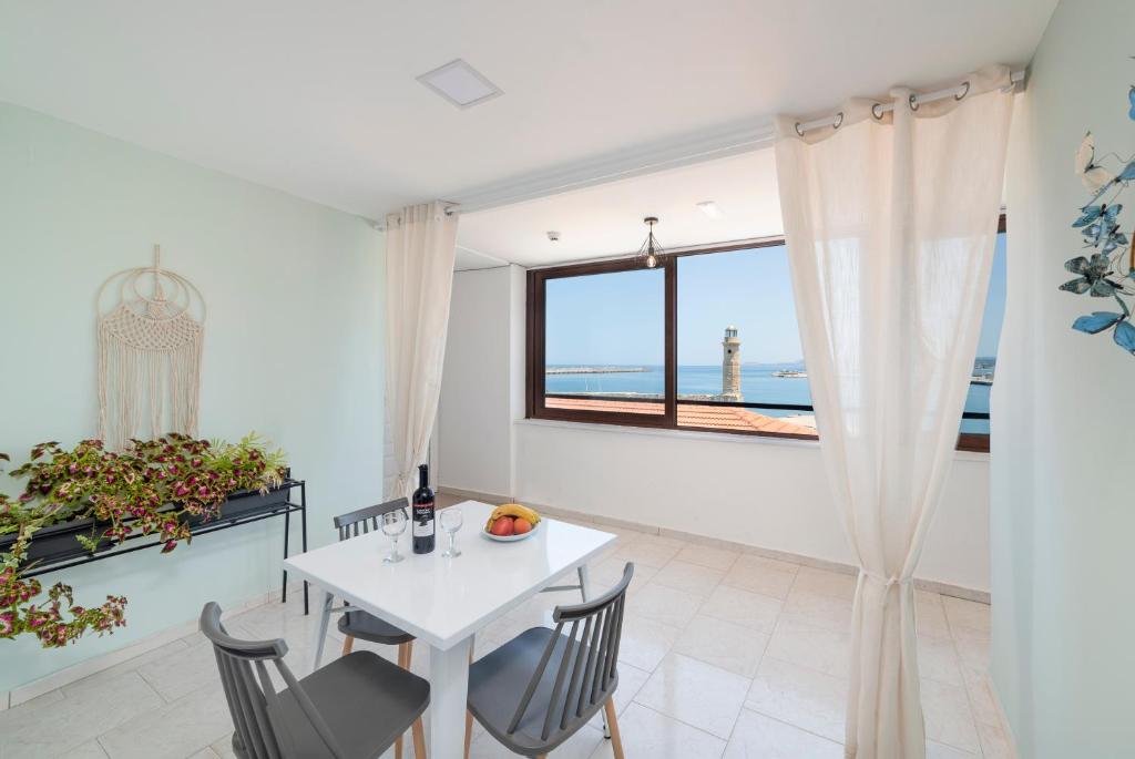 d'une salle à manger avec une table, des chaises et une fenêtre. dans l'établissement Faros Rooms & Suites, à Réthymnon