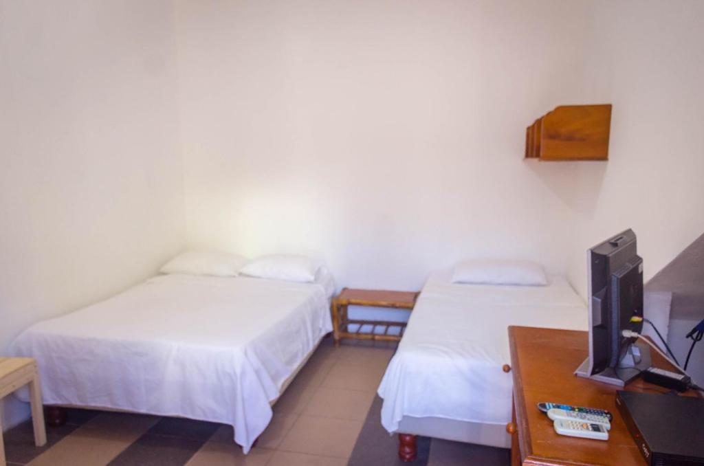 Zimmer mit 2 Betten, einem TV und einem Schreibtisch in der Unterkunft Casa de Huespedes "Darling" in Puerto Baquerizo Moreno