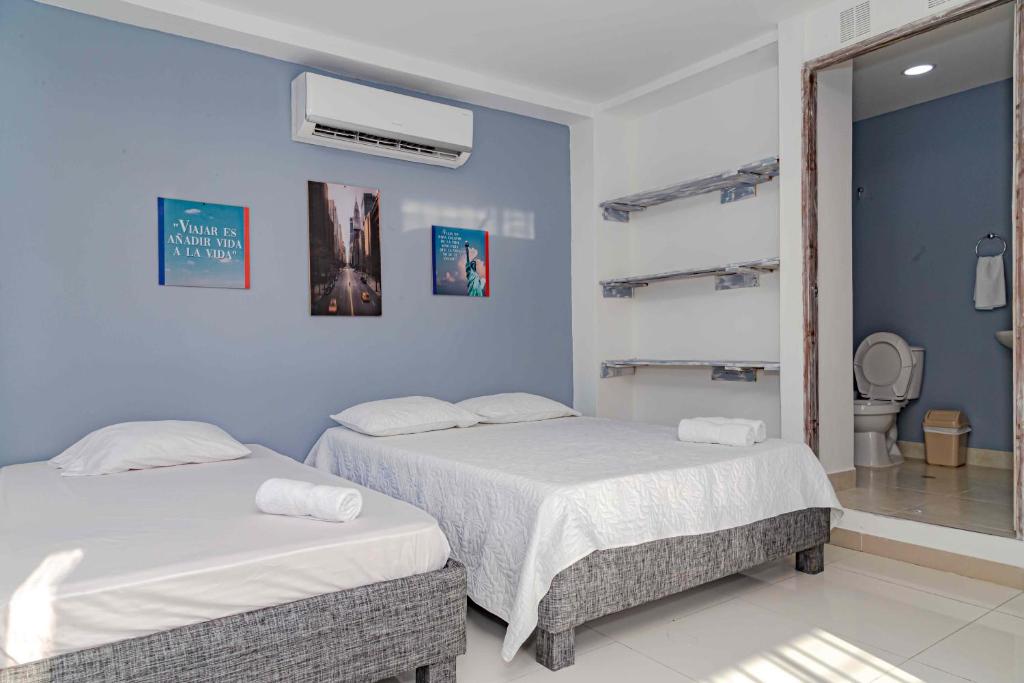 two beds in a room with blue walls at Luna Cartagena Airport Hotel in Cartagena de Indias