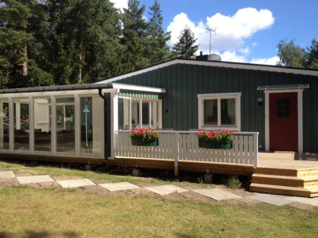 une maison verte avec des fleurs devant elle dans l'établissement Holiday House in Oknö, Mönsterås, à Mönsterås