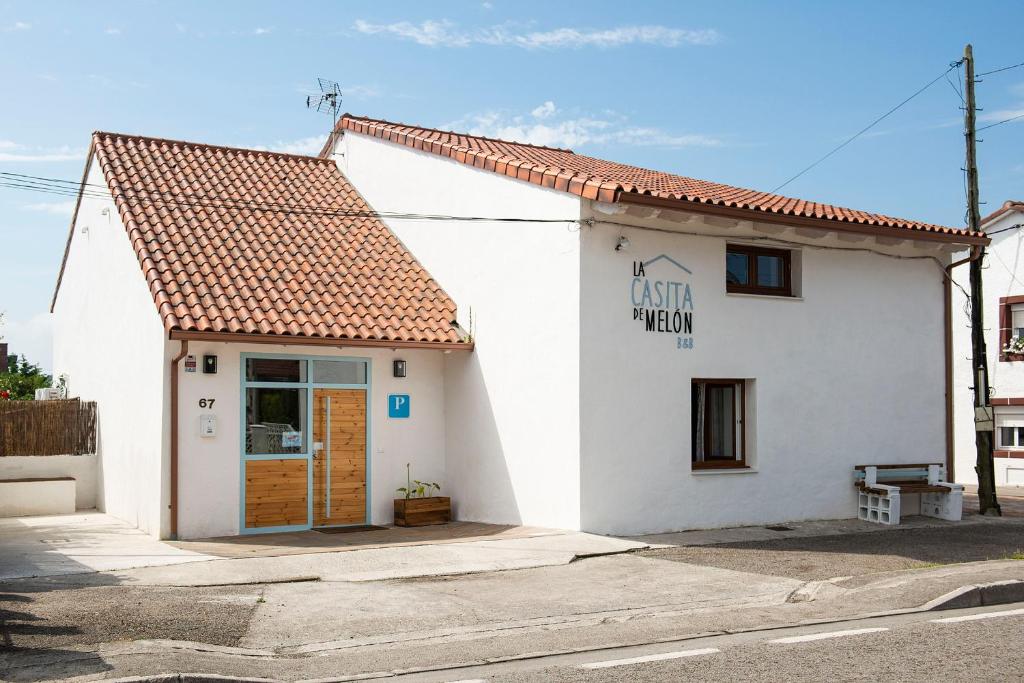 een klein wit gebouw met een bord erop bij La Casita de Melón in Suances