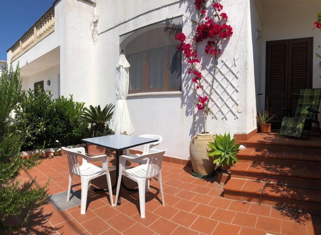 un patio con mesa, sillas y flores en Maison di Leuca, en Leuca