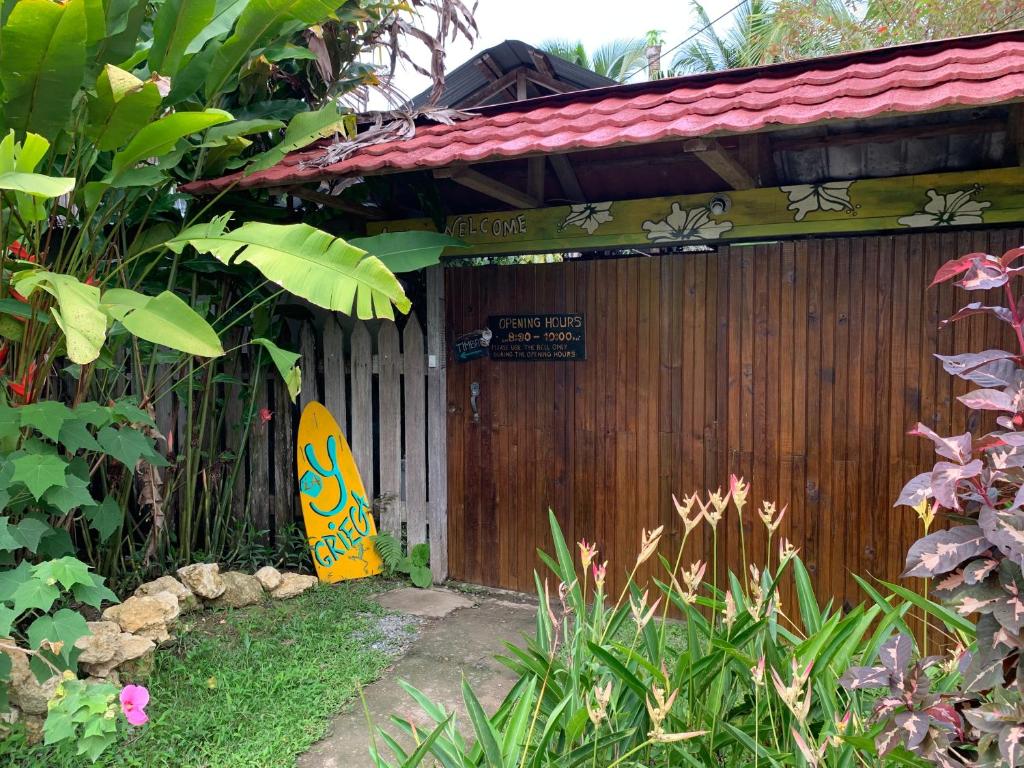 un edificio in legno con una tavola da surf di fronte di Hostal Camping La Y Griega a Bocas del Toro