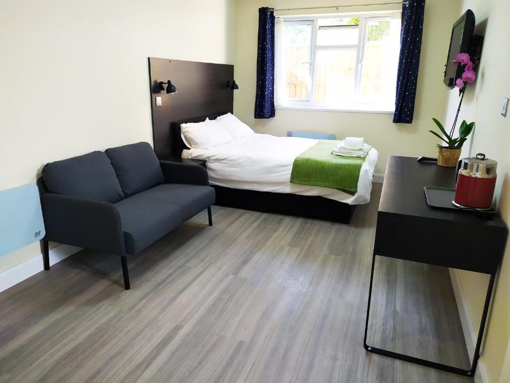 um quarto com uma cama, um sofá e uma cadeira em The Yew Studio - Self contained one bed studio flat with parking em Oxford