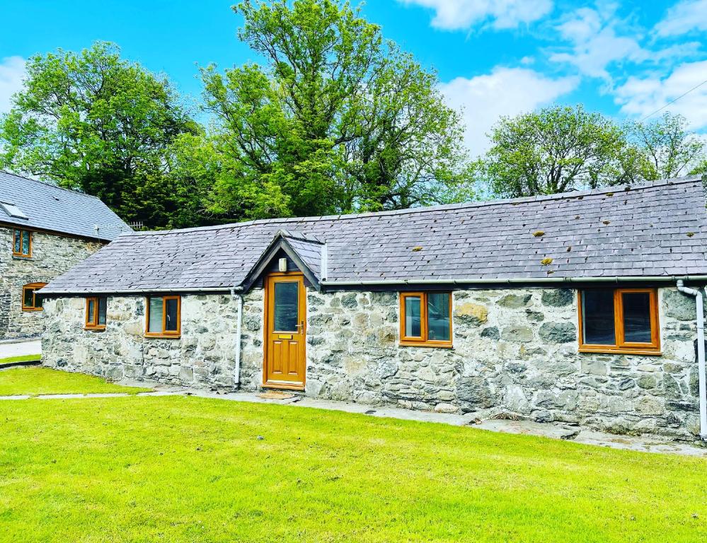 a stone house with a green lawn in front of it at Cwt Mochyn in Corwen