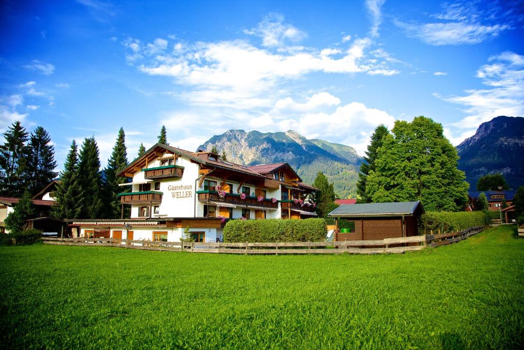 a house in a field with mountains in the background at Gästehaus Weller in Oberstdorf