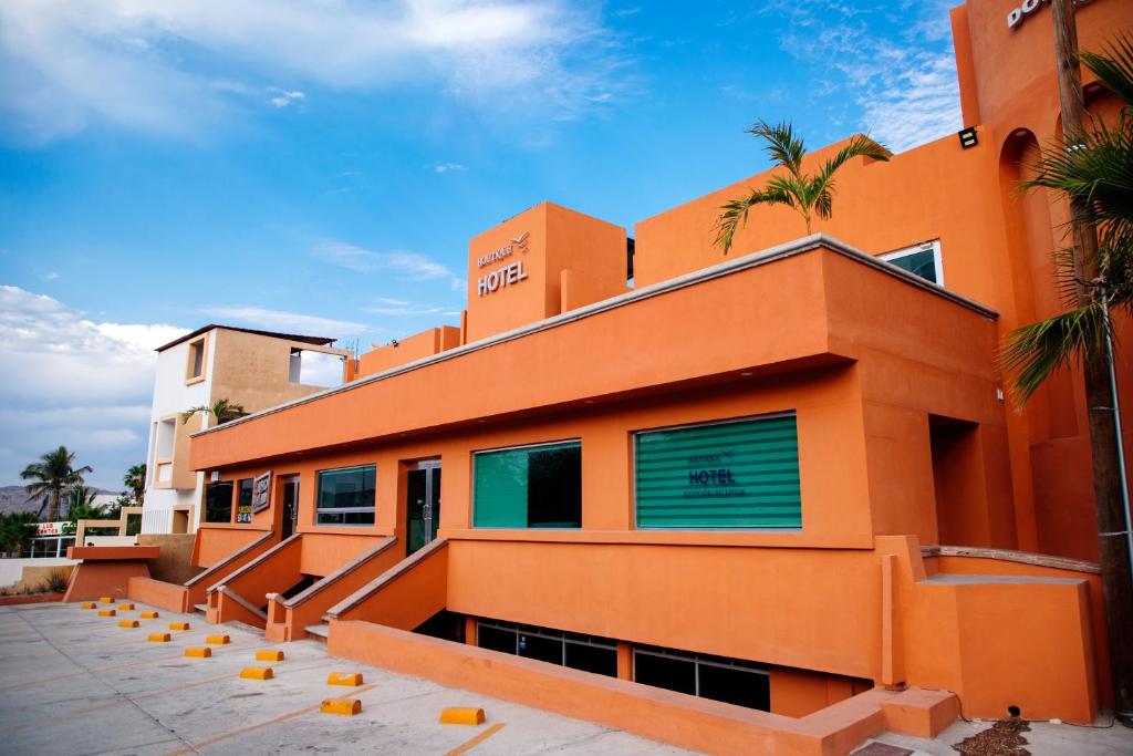 un bâtiment oranger avec des palmiers devant lui dans l'établissement Hotel Boutique Plaza Doradas, à San José del Cabo