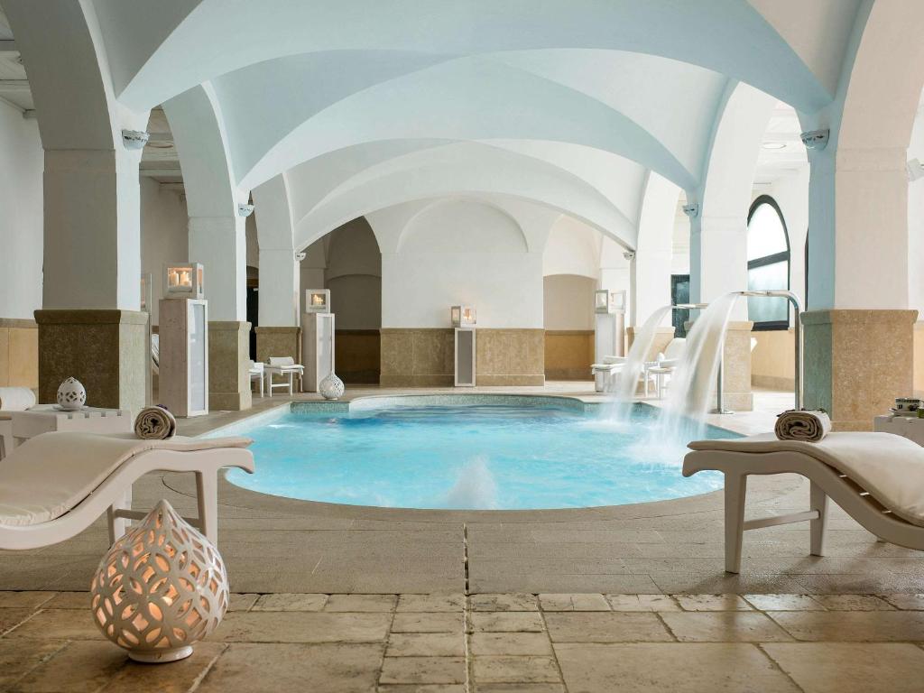 a large pool with a water slide in a building at Borgobianco Resort & Spa Polignano - MGallery Collection in Polignano a Mare