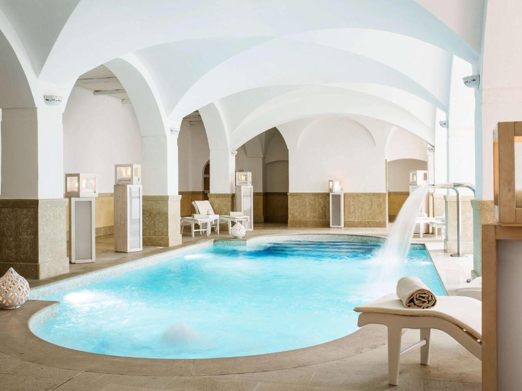 a swimming pool with a fountain in a building at Borgobianco Resort & Spa Polignano - MGallery Collection in Polignano a Mare