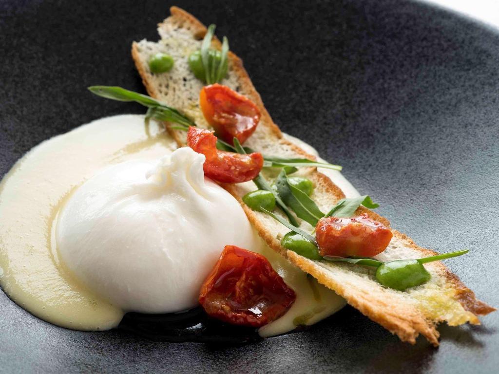a sandwich with a egg on a black plate at Borgobianco Resort & Spa Polignano - MGallery Collection in Polignano a Mare