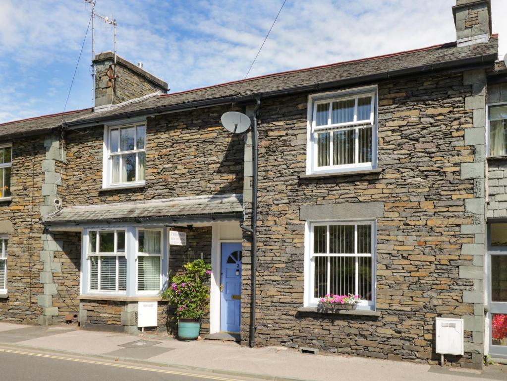a brick house with a blue door and white windows at Two Tweenways in Ambleside