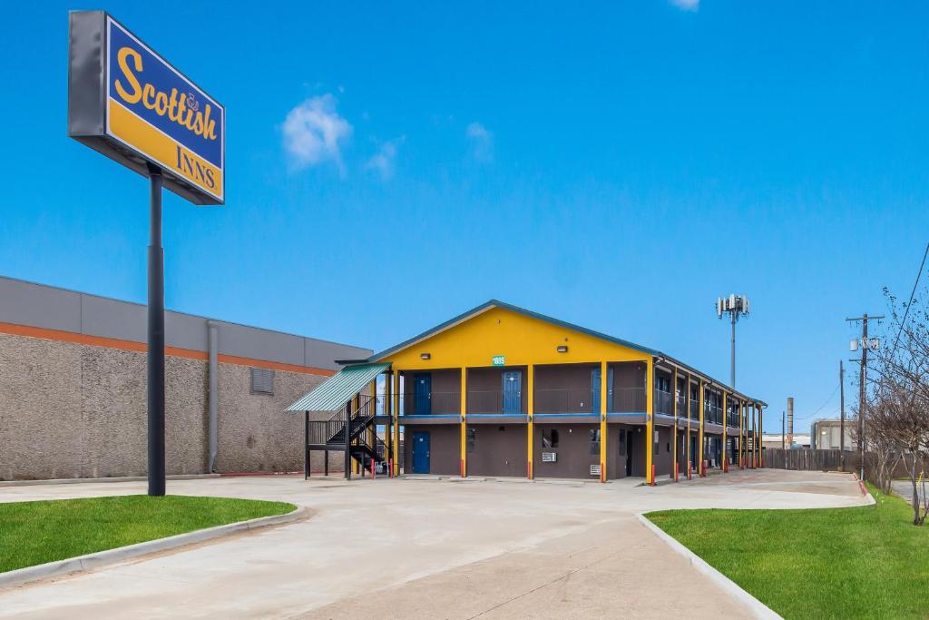 a yellow building with a street sign in front of it at Scottish Inns in Carrollton