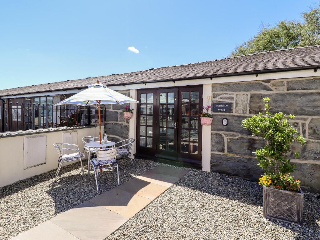 a patio with an umbrella and a table and chairs at Maritime Mews, 6 The Oakleys in Porthmadog