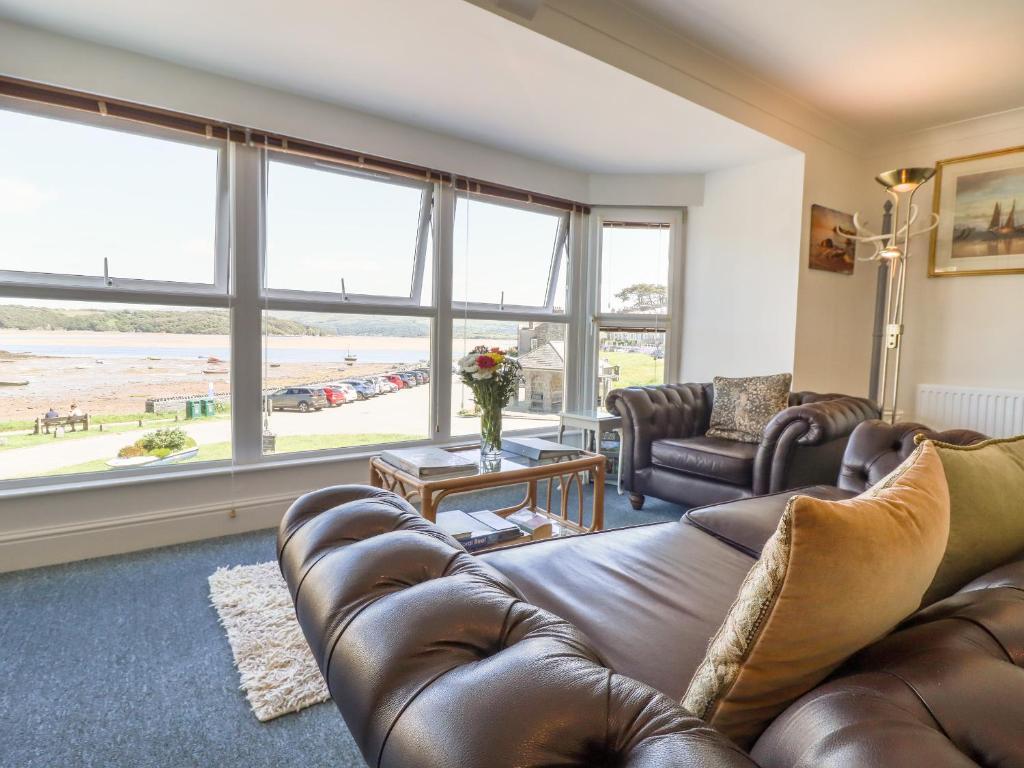 a living room with a brown leather couch and windows at Sea View apartment in Porthmadog