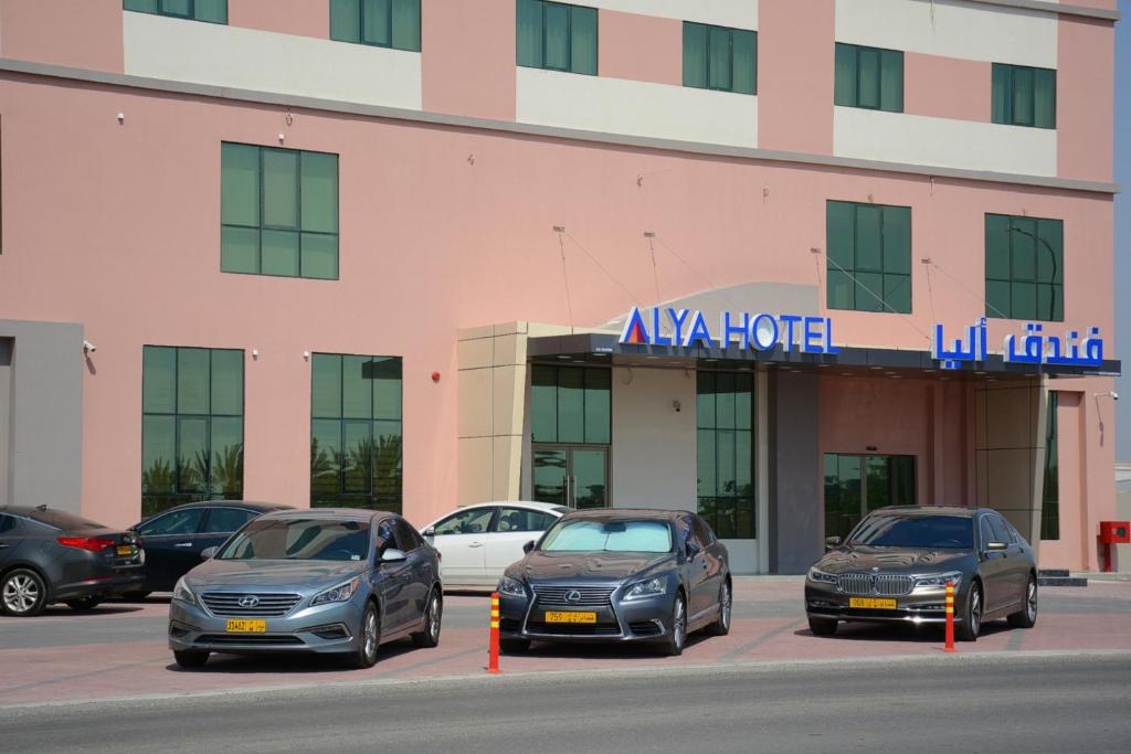 ALYA Hotel في بركاء: مجموعة سيارات متوقفة أمام مبنى
