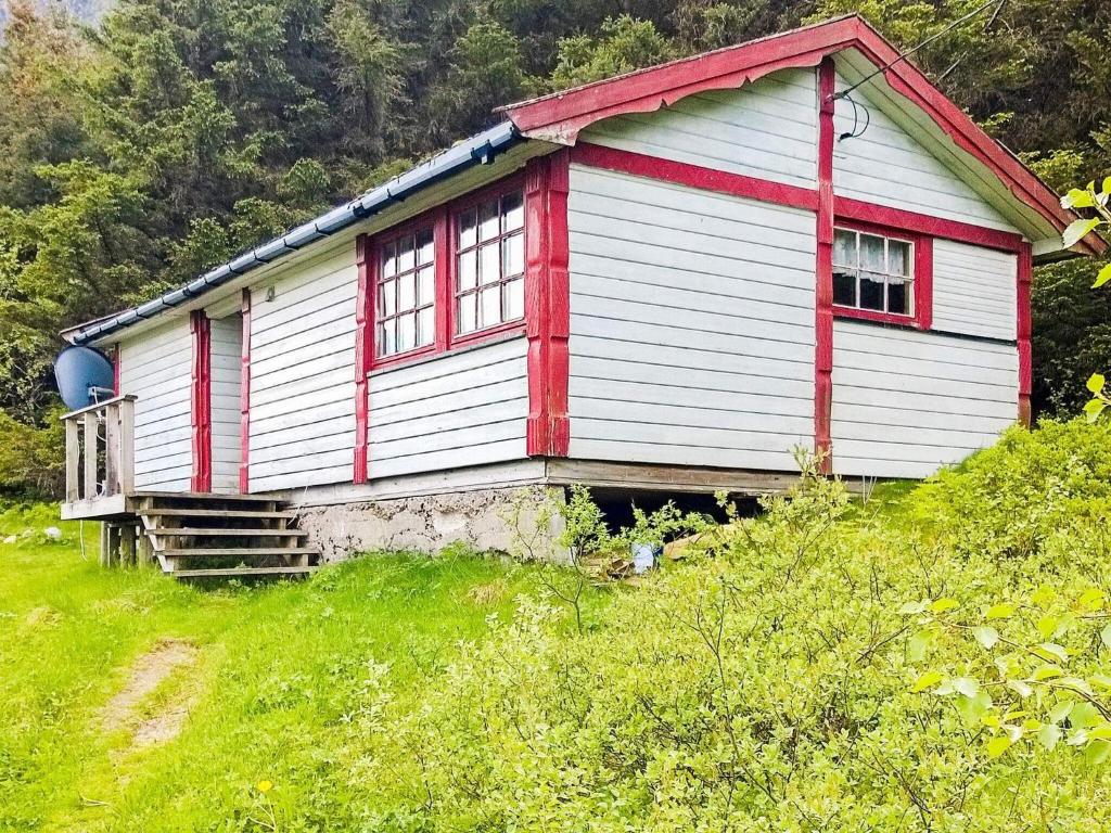 una pequeña casa roja y blanca en una colina en 5 person holiday home in ENGAV GEN en Åmnes