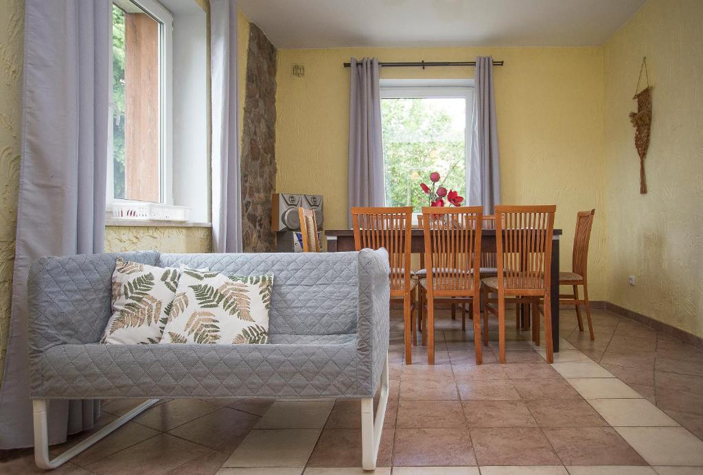 - un salon avec un canapé et une table avec des chaises dans l'établissement Happy Bison - A 5 Bedroom House With A Garden, à Białowieża