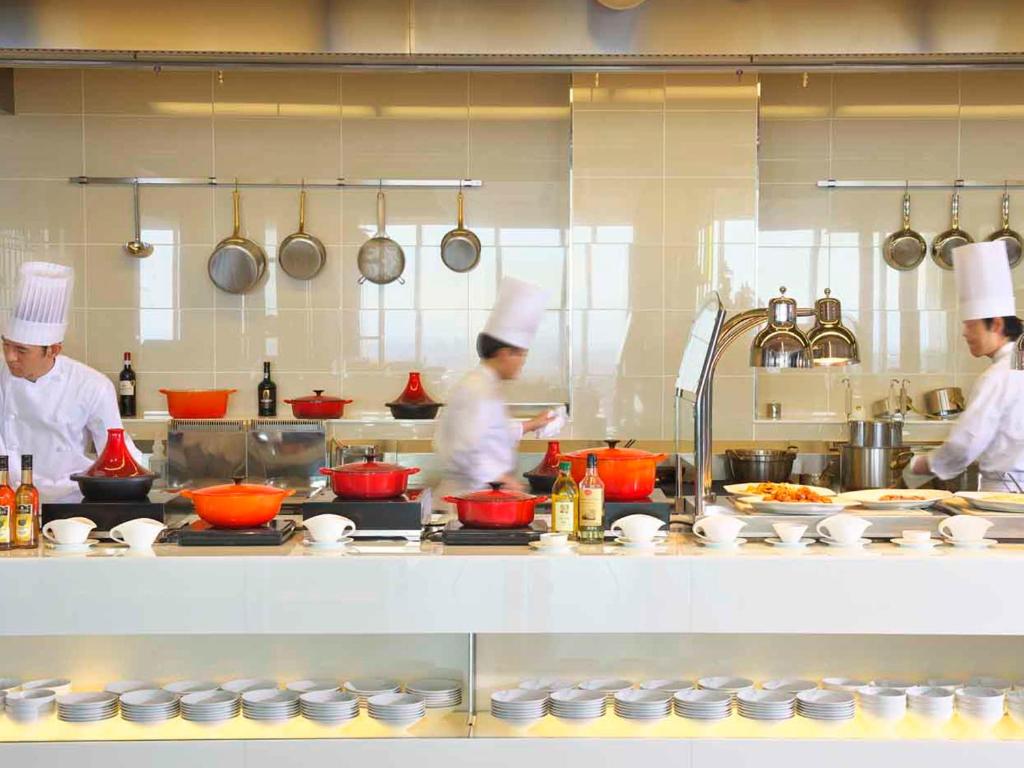 three chefs working in a kitchen preparing food at Osaka Marriott Miyako Hotel in Osaka