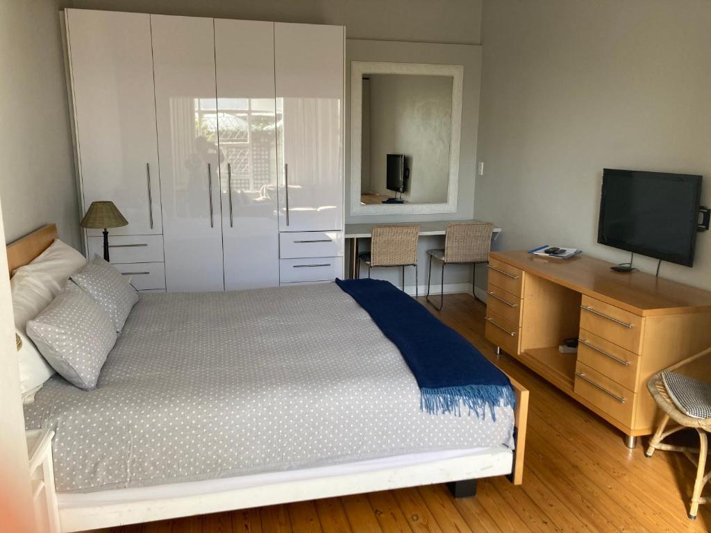 een slaapkamer met een bed, een bureau en een televisie bij The Fox Hole in Krugersdorp