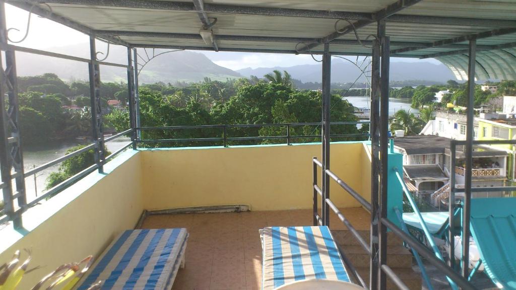 a balcony with two chairs and a view of a river at Tyvabro Guesthouse in Mahébourg