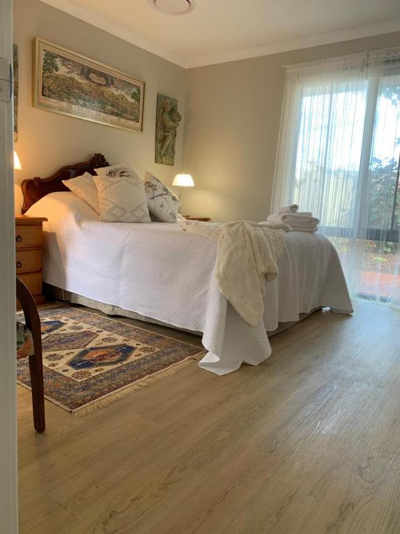 a bedroom with a bed with white sheets and a rug at Forest Retreat Bed and Breakfast in Margaret River Town