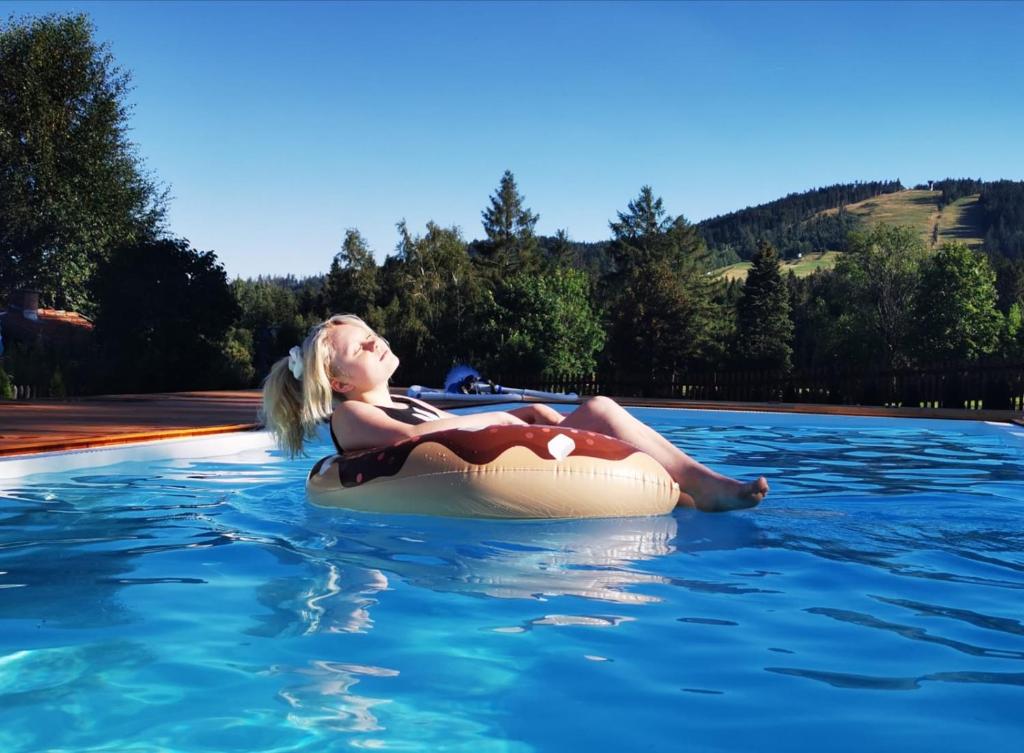 a woman is sitting on an inner tube in the water at Hotel Schäfflerhof in Bischofsmais
