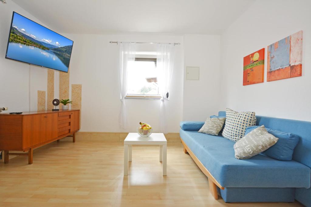 a living room with a blue couch and a table at Ferienwohnung Alpenblick in Villach