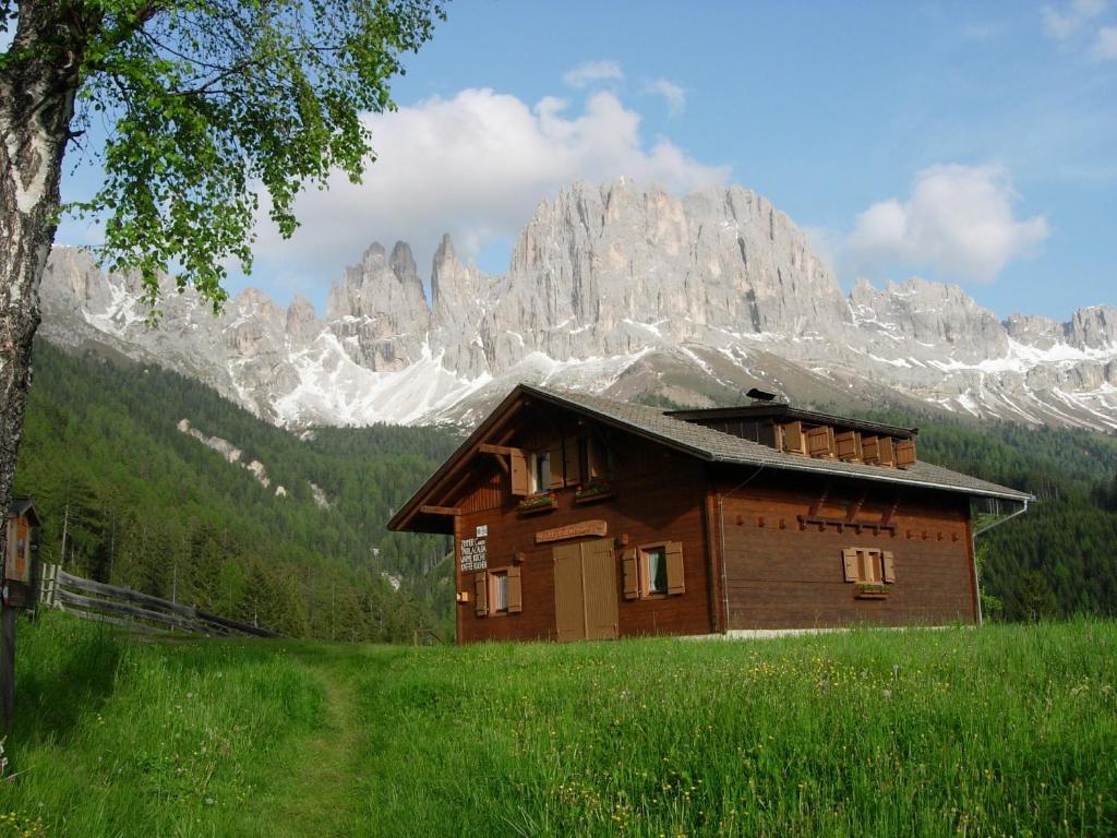 ein Haus auf einem Feld vor einem Berg in der Unterkunft Berghütte Plafötschalm in Tiers