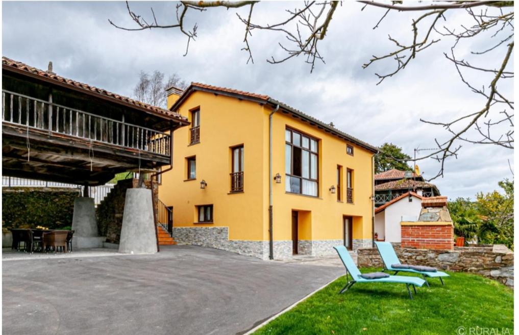 a yellow house with two blue chairs in the yard at Casa Hortensia in Salas