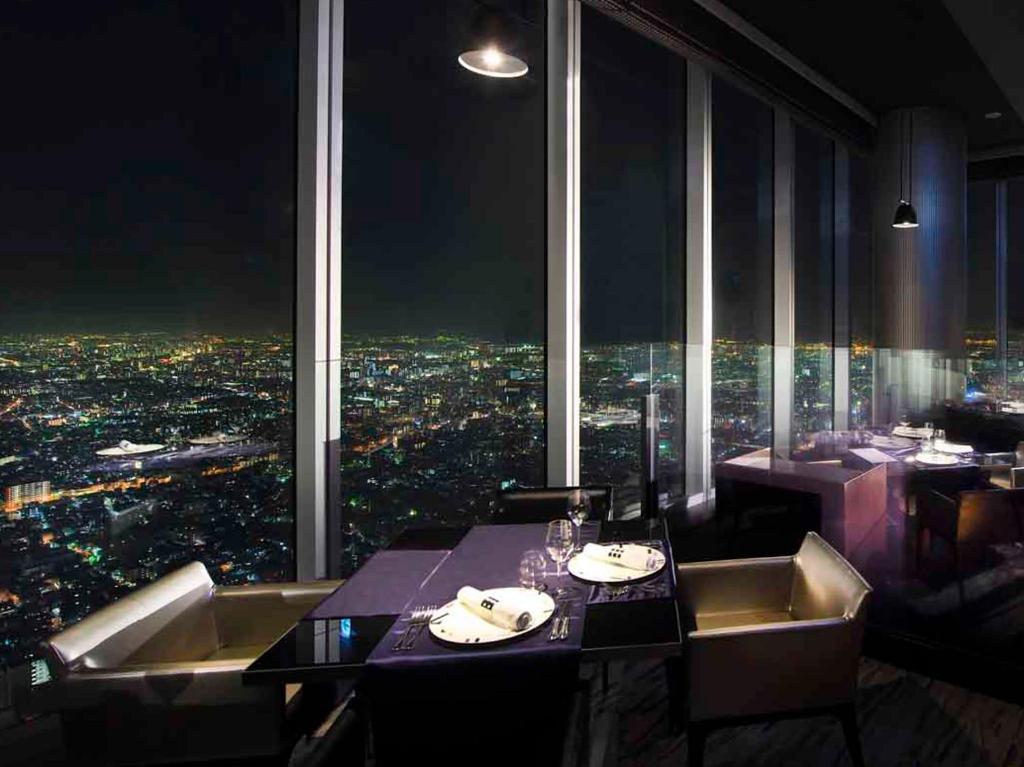 a restaurant with a view of a city at night at Osaka Marriott Miyako Hotel in Osaka