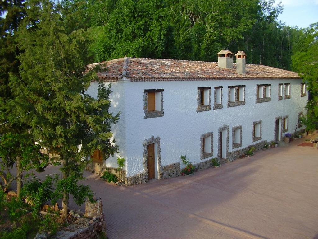 una gran casa blanca con un árbol delante en El Molino de Iramala, en Reolid