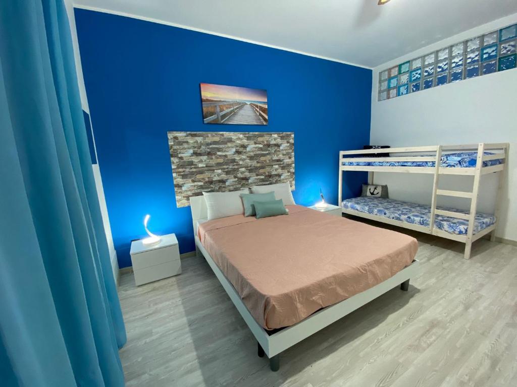 1 dormitorio con una pared azul, 1 cama y literas en Vista Eolie Milazzo- Apartments, en Milazzo
