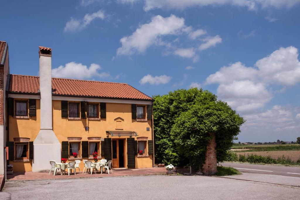 a building with tables and chairs in front of it at Agriturismo Le 4 Rose in Vescovana
