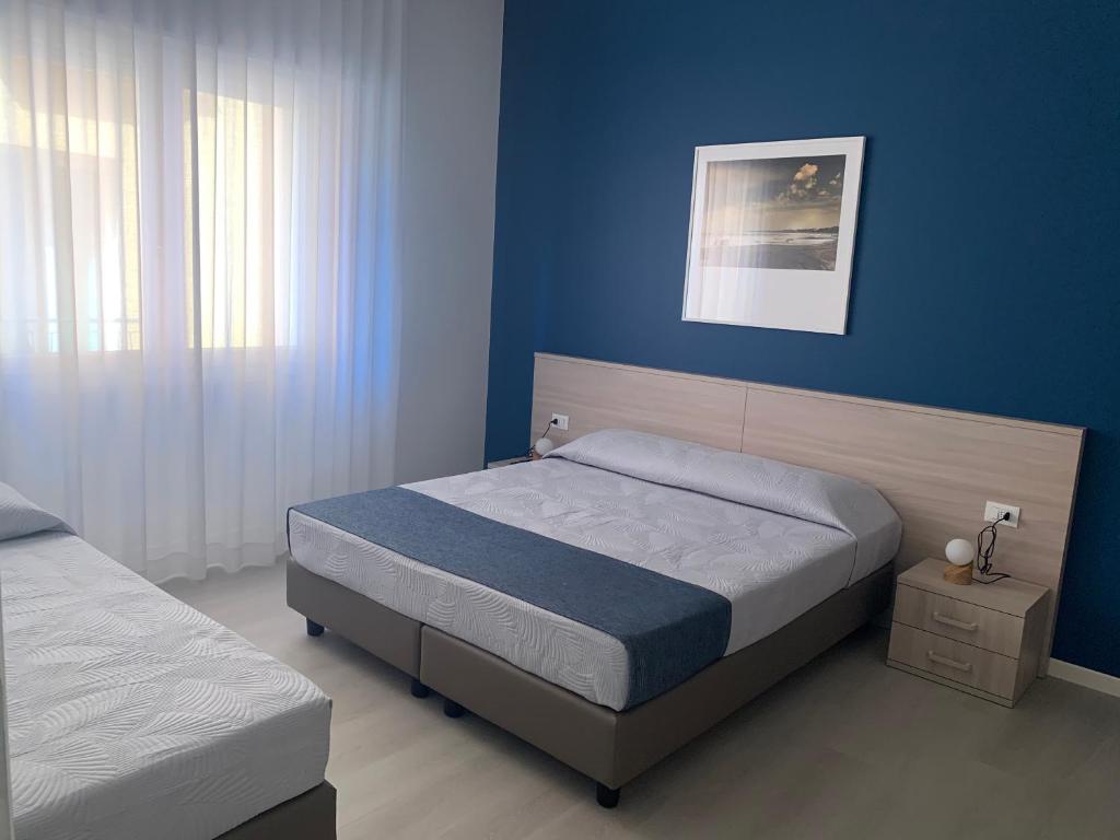 a bedroom with two beds and a blue wall at MAR60 Apartments in Caorle