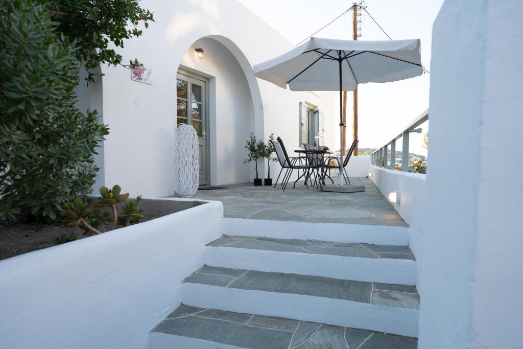 a white house with a patio with a table and an umbrella at Iviskos House Apollonia Sifnos in Apollonia