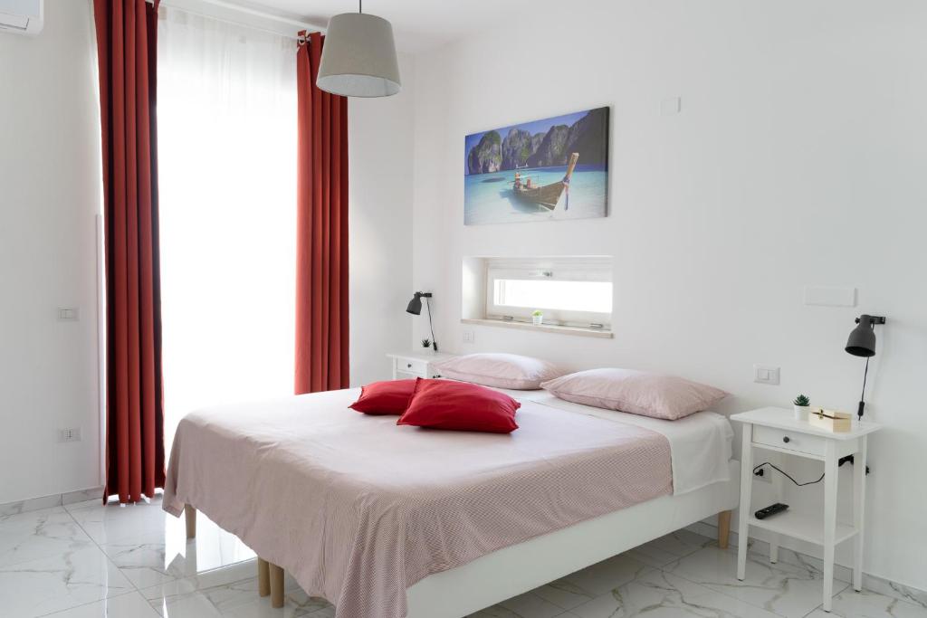 a white bedroom with a bed with red pillows at A casa di Luca B&B in Torchiara