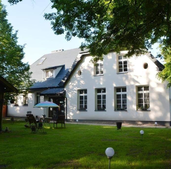 a large white house with a table and chairs in the yard at Gospodarstwo Agroturystyczne Andrzejówka in Gardzień