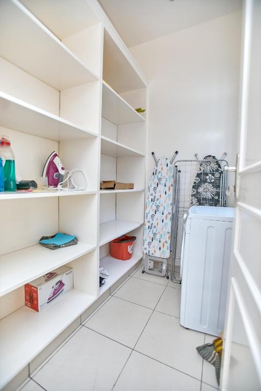 黑角Appartement - Vue sur mer的白色的厨房配有白色的架子和冰箱
