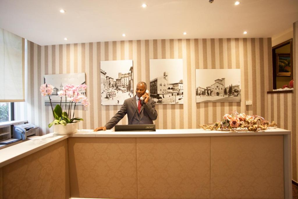 a man talking on a phone at a reception desk at Boutique Hotel Re Enzo in Bologna
