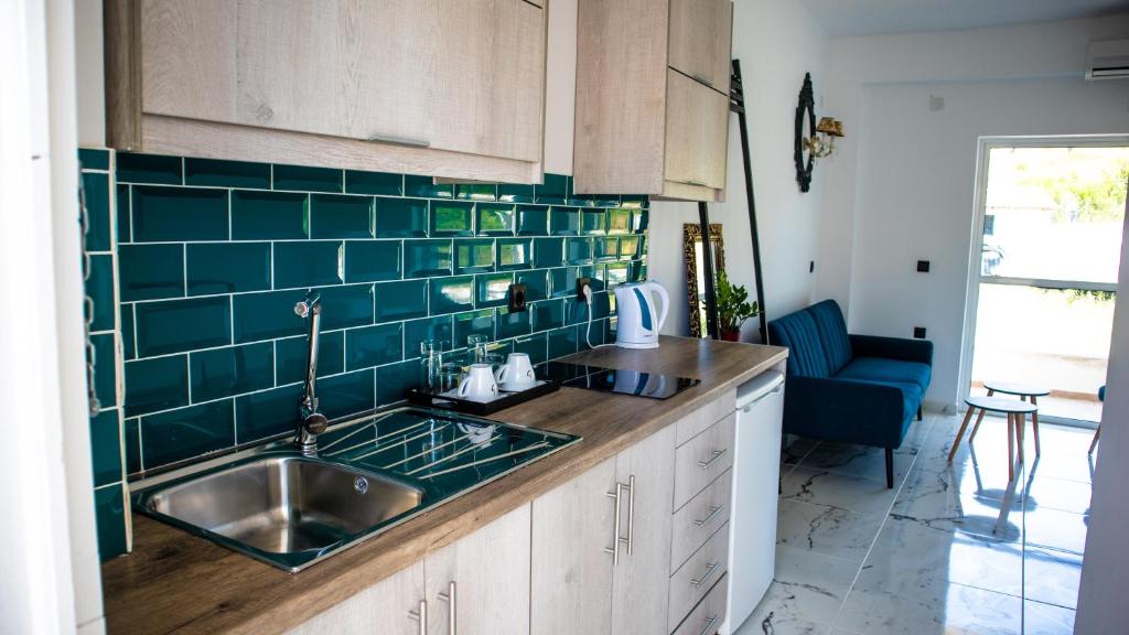 a kitchen with a sink and green tile on the wall at Kalypso studio Resorts in Kavos