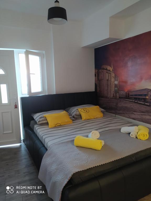 a bedroom with two beds with yellow pillows and a painting at Cvita & Maja in Zadar