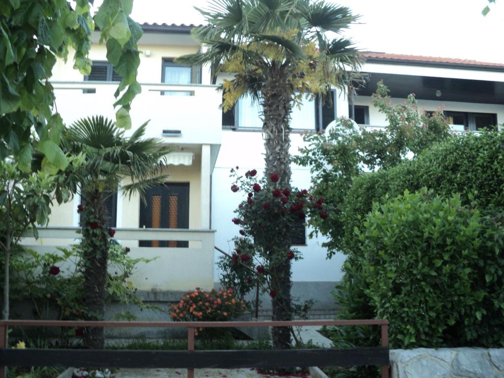 a building with a palm tree in a garden at Apartments Nevenka in Krk