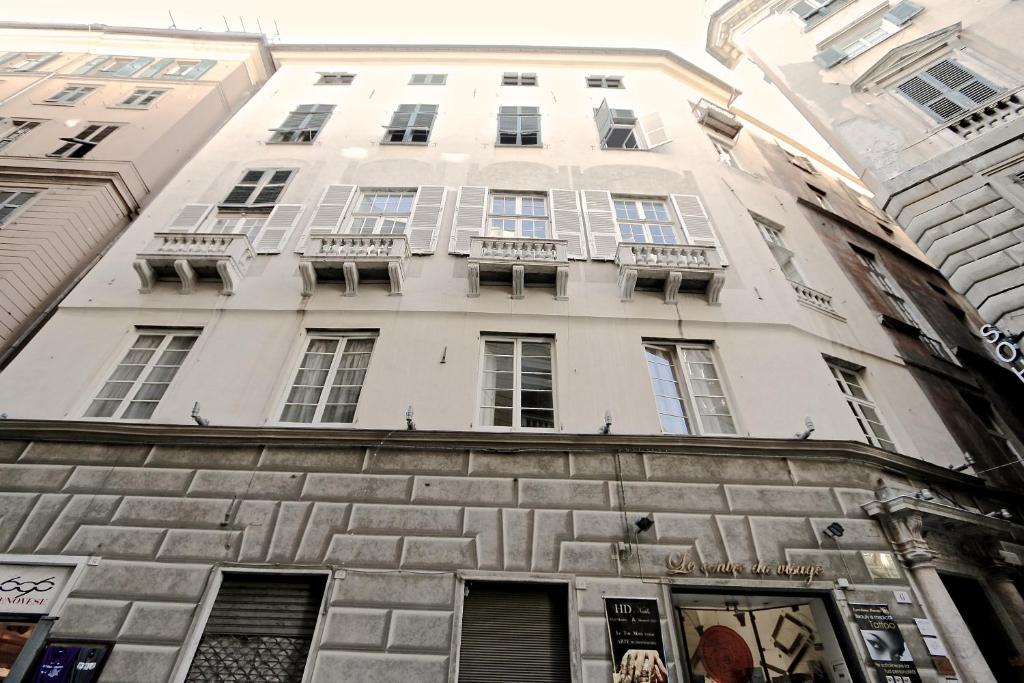 un edificio alto de color blanco con ventanas y balcones. en Palazzo Cambiaso, en Génova