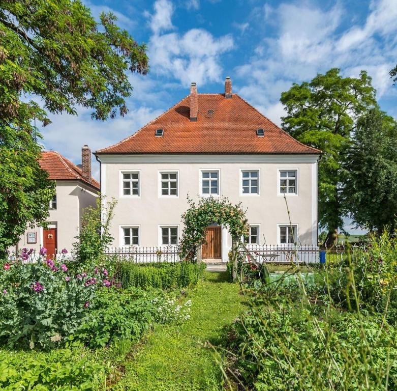 Historischer Pfarrhof Niederleierndorf في Langquaid: بيت ابيض كبير بسقف احمر