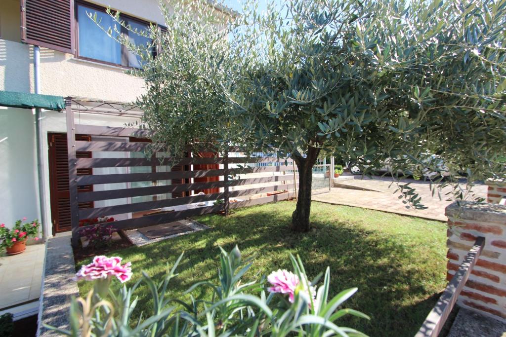 a tree in the middle of a yard with flowers at Apartment Luigi in Poreč