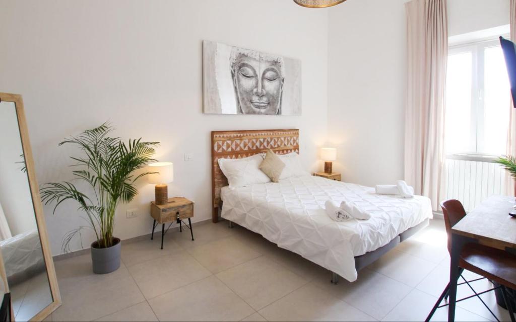 a white bedroom with a bed and a desk and a plant at Travel B&B in Pisa